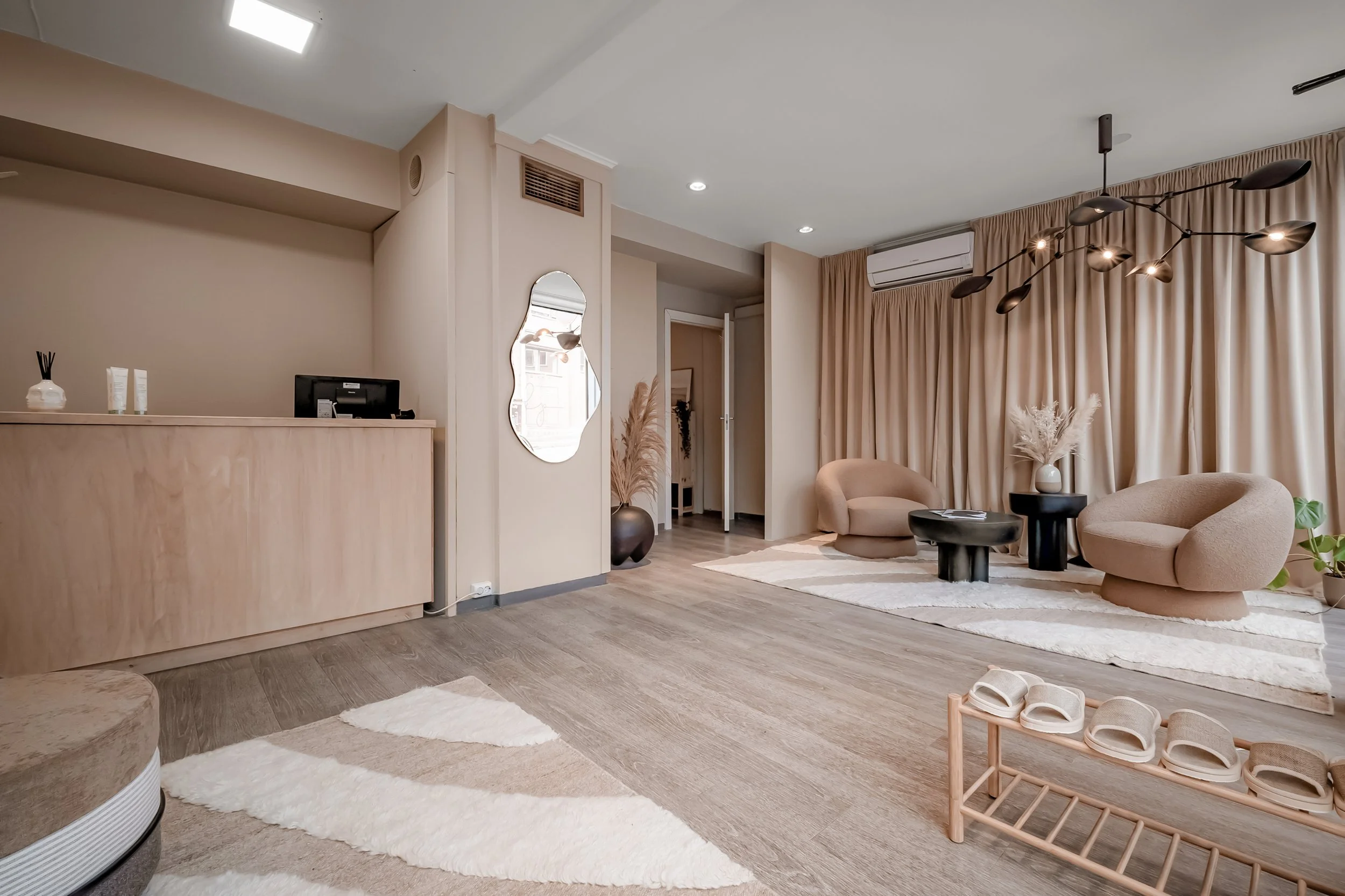 Et lyst og stilrent stueområde med beige og nøytrale toner, to moderne beige sofabordsstoler, en svart bord, store gardiner, dekorative vaser med tørkede blomster, og lys tre-aktig gulv.