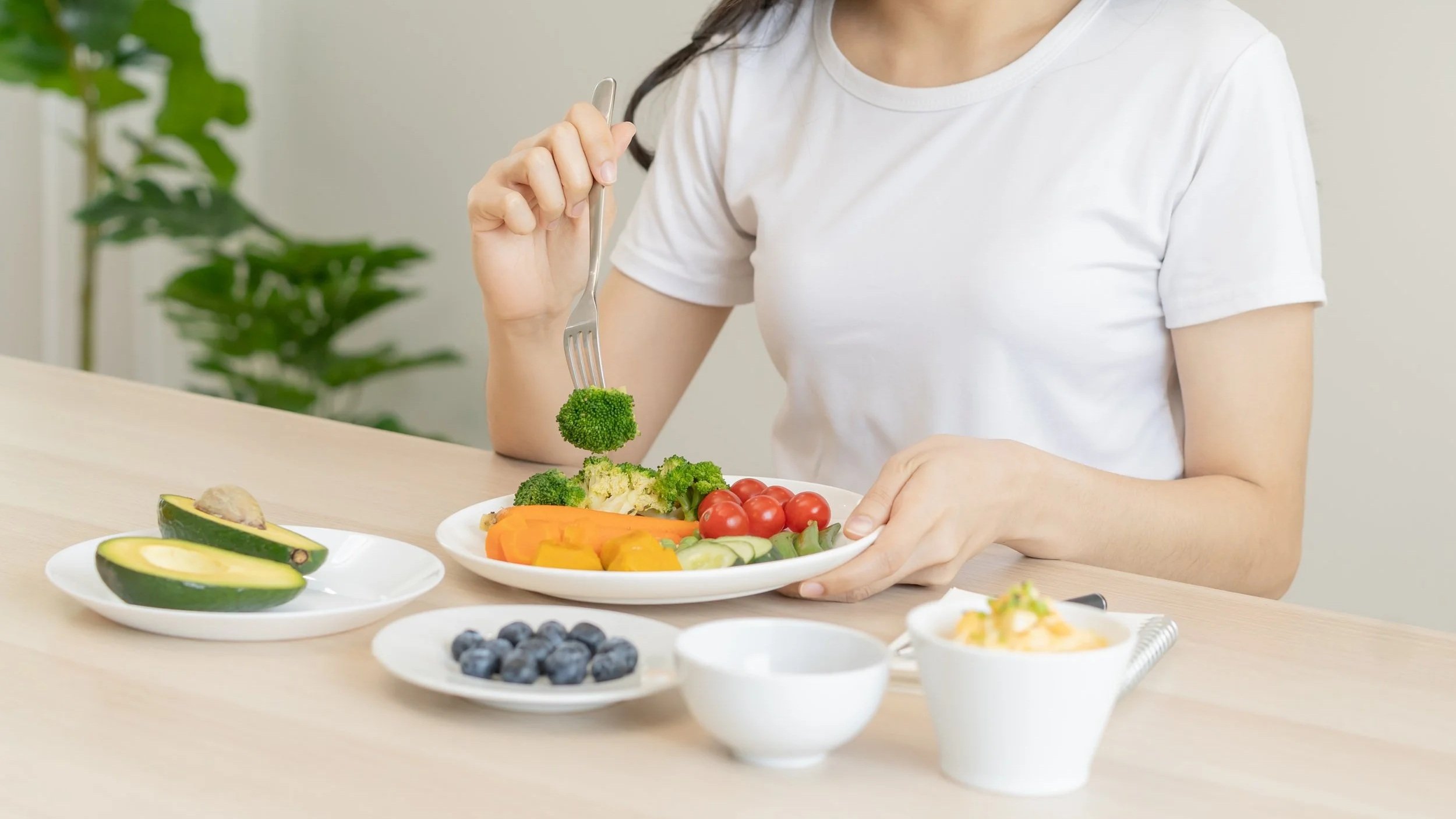 Person enjoying a nutrient-rich meal featuring fresh vegetables, avocado, and berries, highlighting healthy eating and plant-based nutrition.
