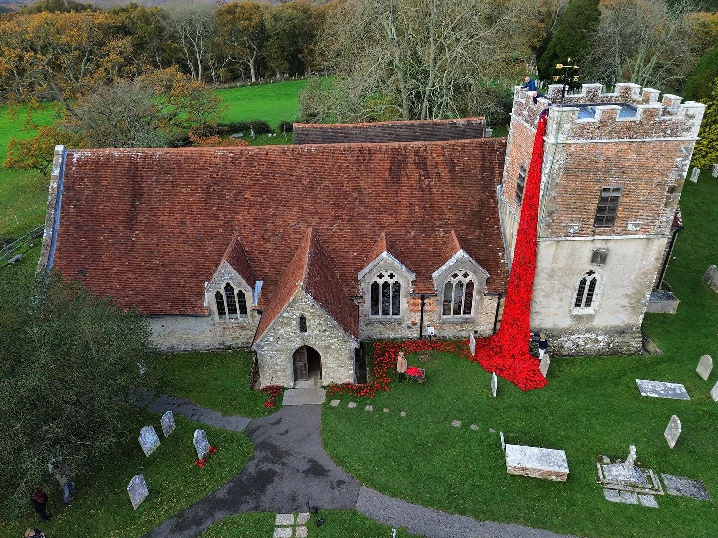 A POP-PY OF COLOUR! A huge knitted poppy &lsquo;waterfall&rsquo; creates a splash of colour as it cascades down the tower of St. John&rsquo;s Church, Boldre, New Forest, Hants. 

Volunteers add finishing touches to the display. The congregation were 