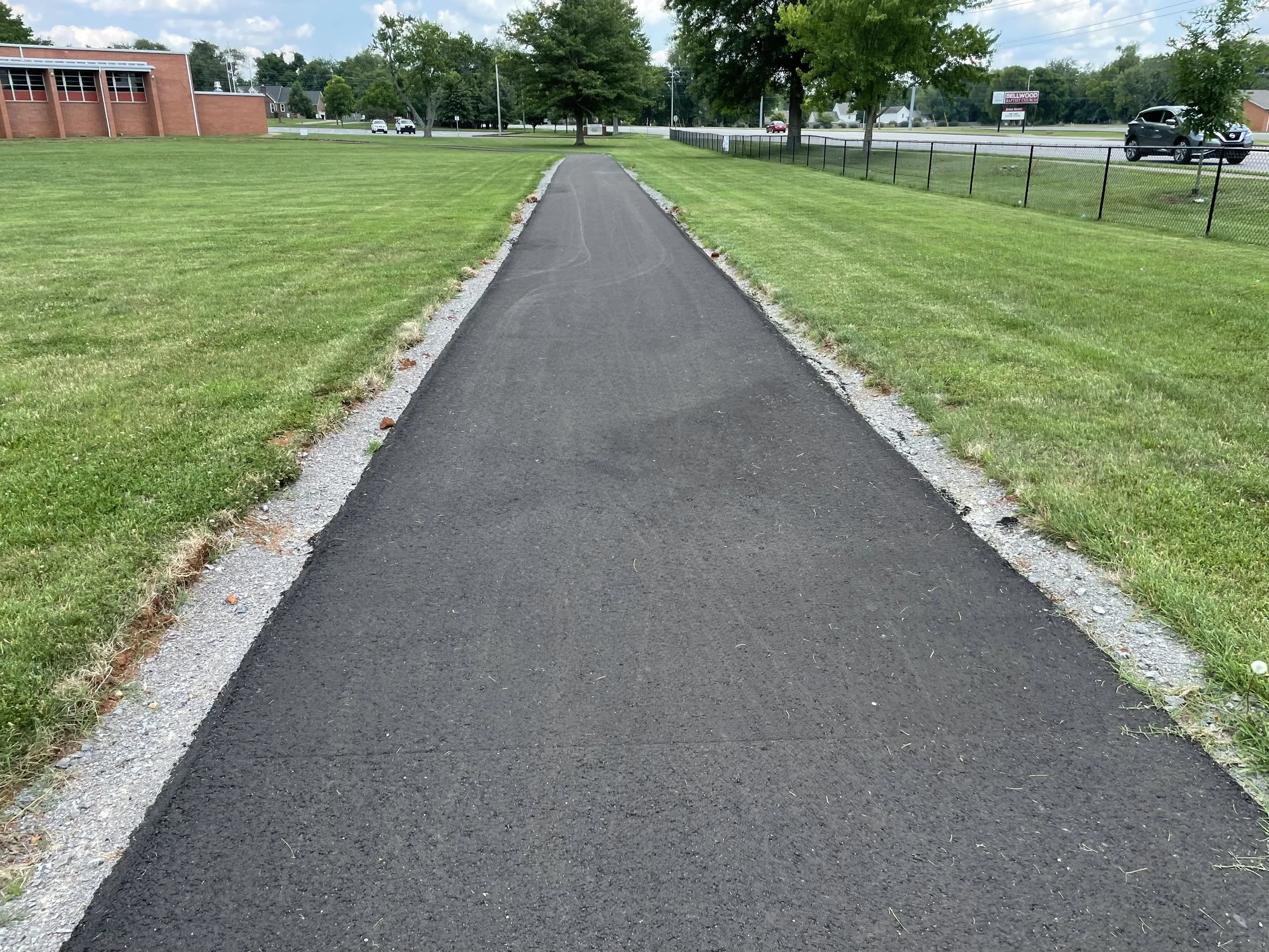 The paving of a walking trail in Rutherford County TN in Murfreesboro at Discovery Middle School in TN using asphalt base stone and asphalt paving to form the walking trail for use as a pedestrian path