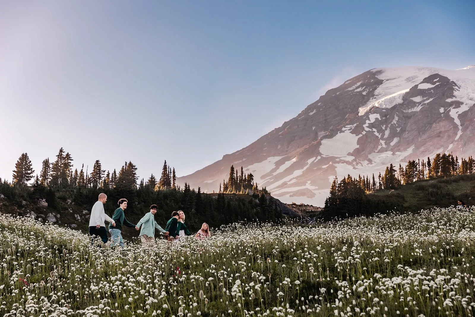 Family walks up the hillside with Mt. Rainier in the background