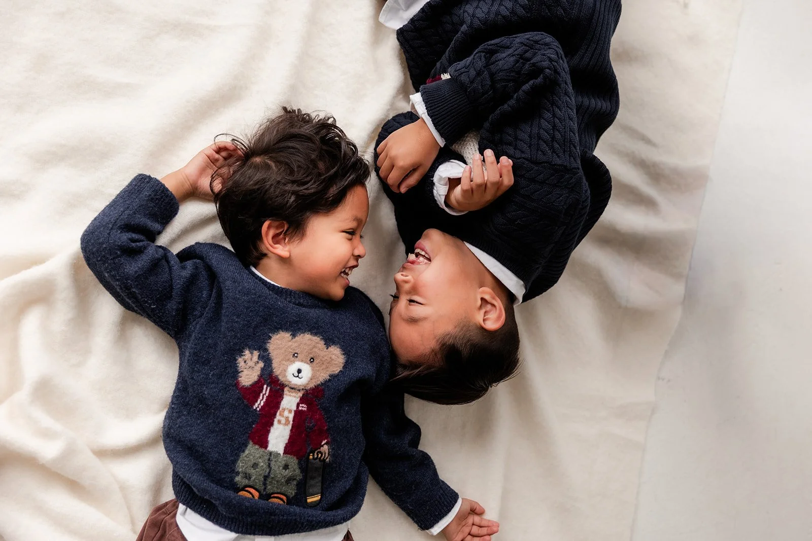 Two brothers lay on the floor laughing with each other