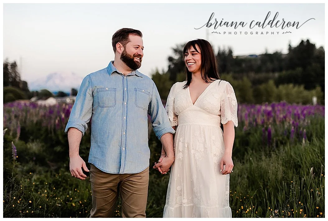 Couple walks through lupine farm with Mt. Rainier behind