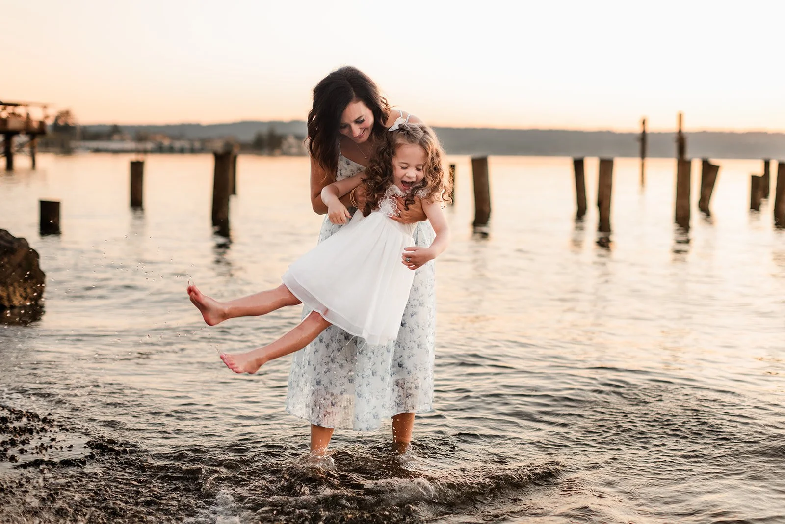 Mom and daughter splash on the shore at golden hour