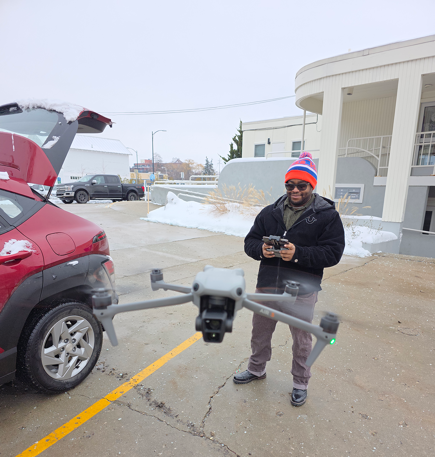 Man stands stands outside in cold, wintry weather piloting a drone