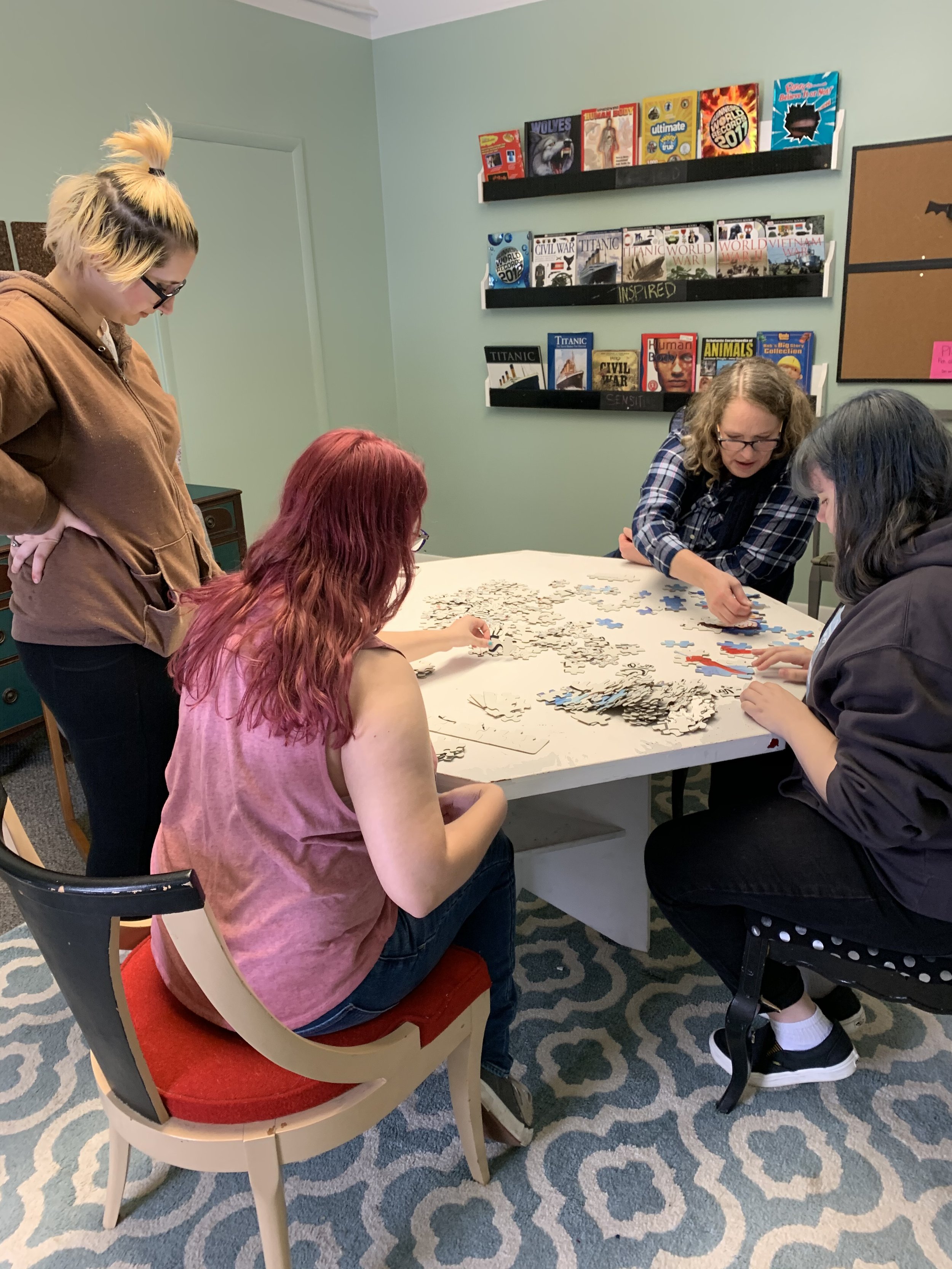 Four women sit at a table doing a puzzle