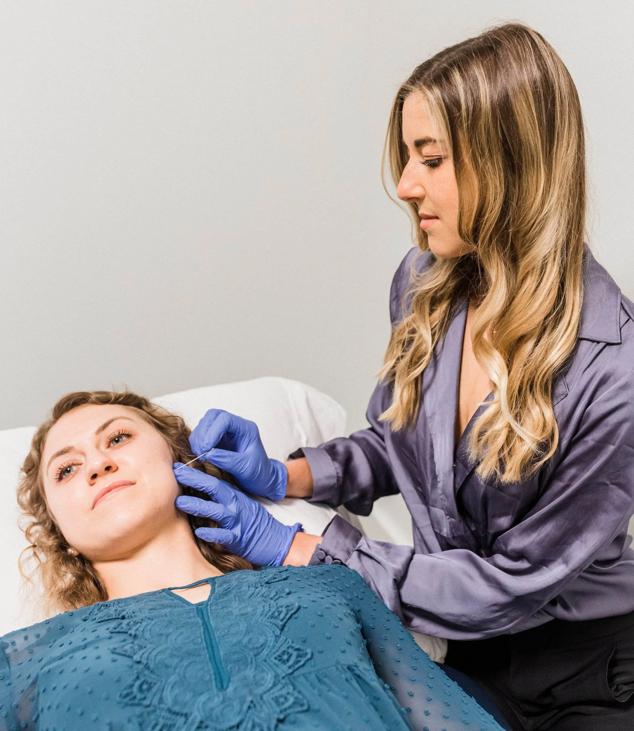 Therapist in purple blouse performing dry needling on female client