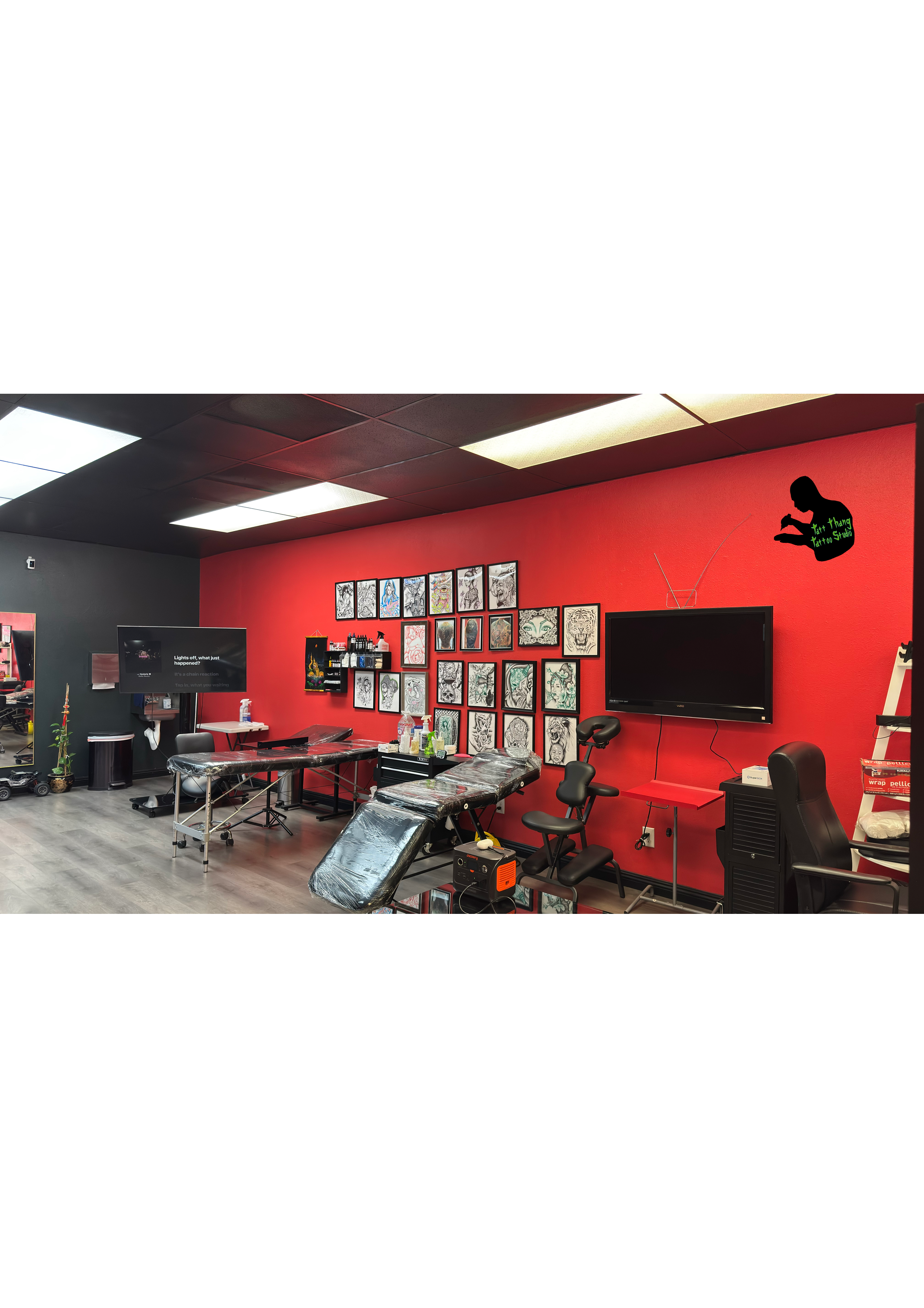 Tattoo studio interior with tattoo chairs, wall art, large TV, tattoo equipment.