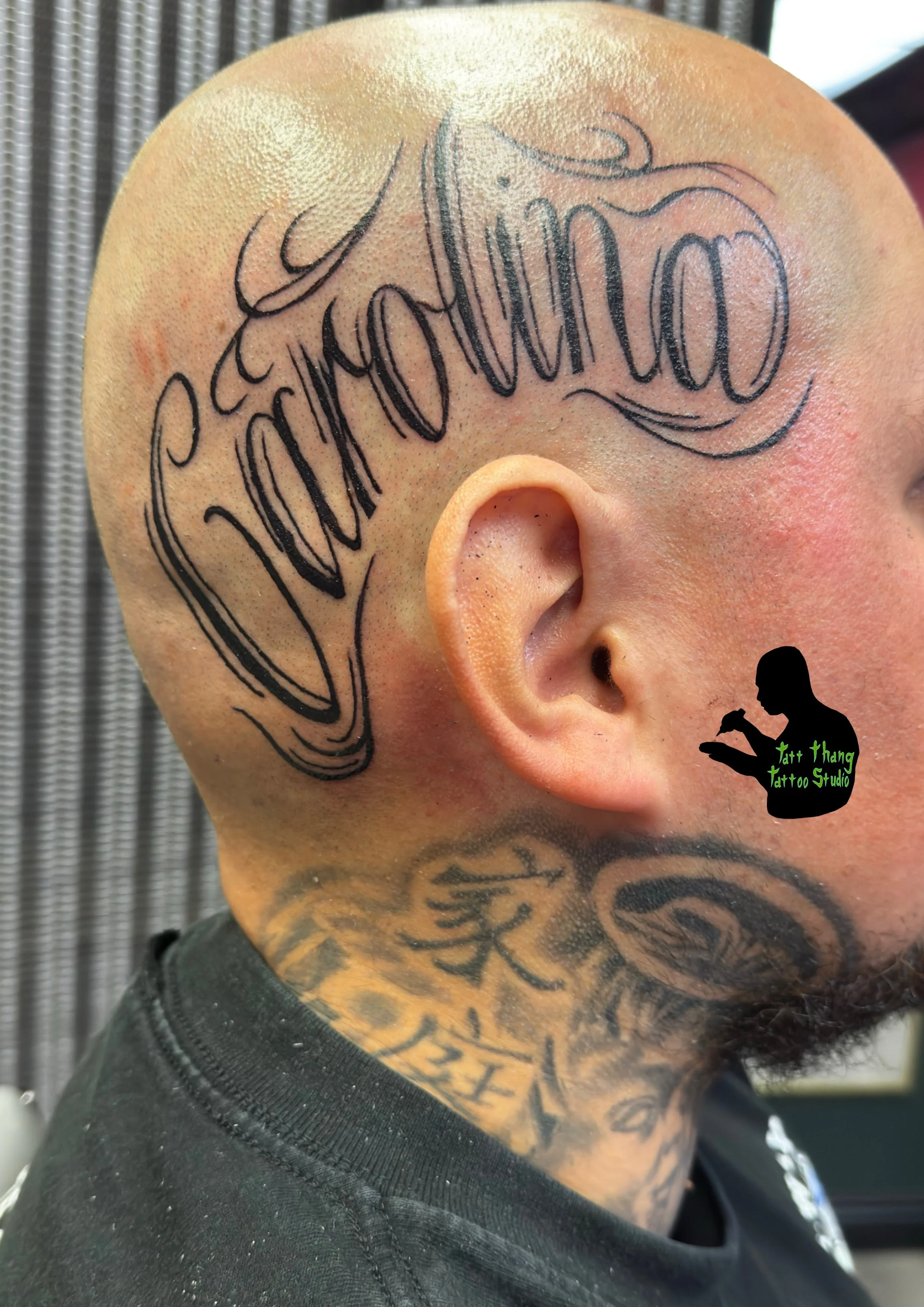 Tattoo of a name in cursive font on the person's shaved head.