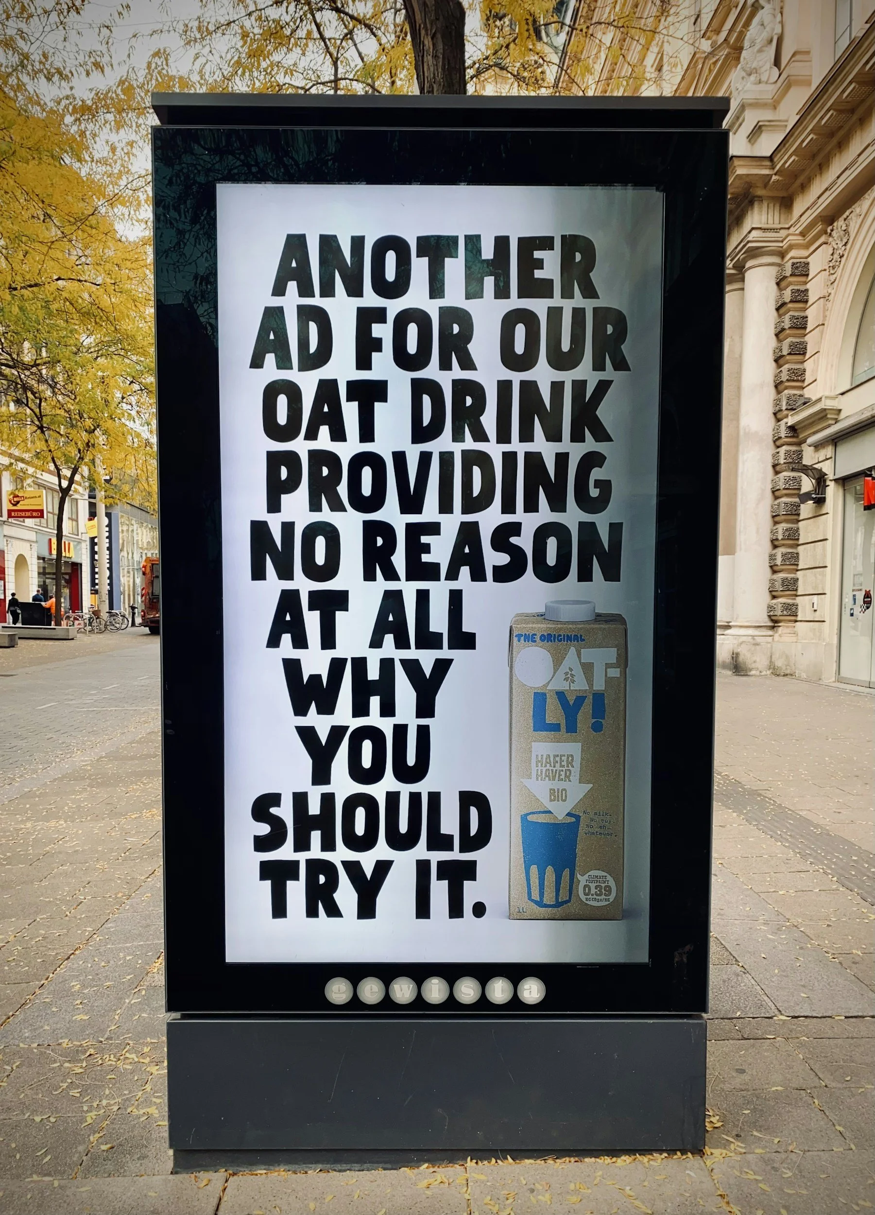 Billboard advertisement for oat drink with bold black text stating "Another ad for our oat drink providing no reason at all why you should try it," alongside a picture of oat drink packaging.