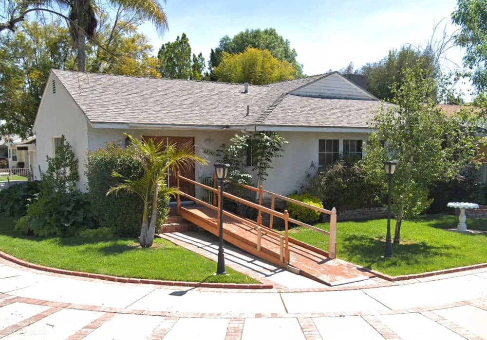 Front view of AAA Royal Senior Living Facility in Tarzana, CA with an accessibility ramp and landscaped front yard.