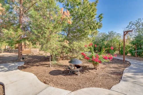 Tranquil garden area at Manor on Paradise Assisted Living with paved walking paths, greenery, and a central firepit for outdoor relaxation.