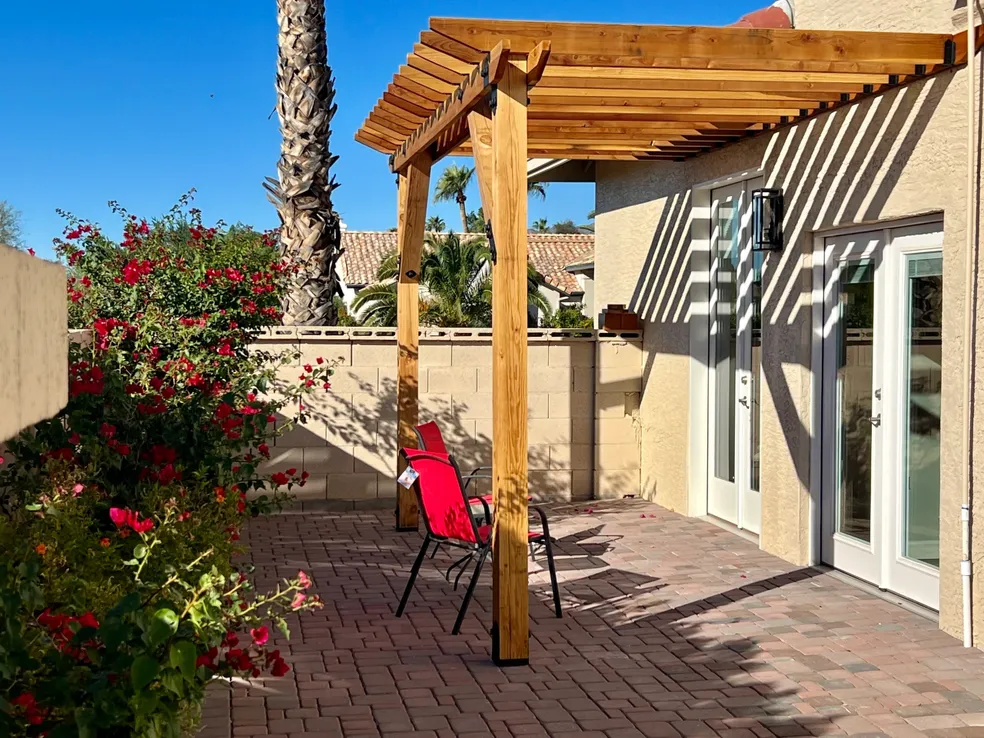 Cozy outdoor patio area at Desert Cove Assisted Living in Scottsdale, AZ, featuring a wooden pergola, comfortable seating, and beautiful garden surroundings — perfect for relaxation and outdoor socializing.