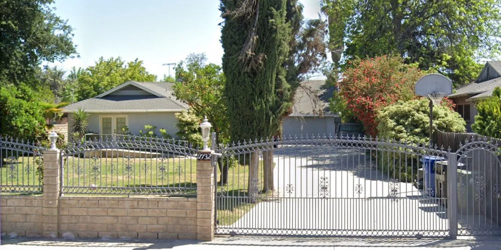 Exterior view of Chateau Encino Care, Inc., a secure residential senior living home in Los Angeles featuring a gated entrance and lush greenery, where a professional home caregiver provides personalized support for elderly residents.