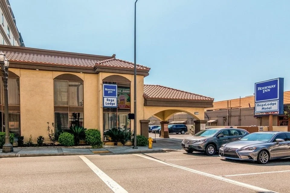 Front view of Rodeway Inn Regalodge in Glendale, California, showing the beige building with red-tiled roof, street view, and parked cars in front.