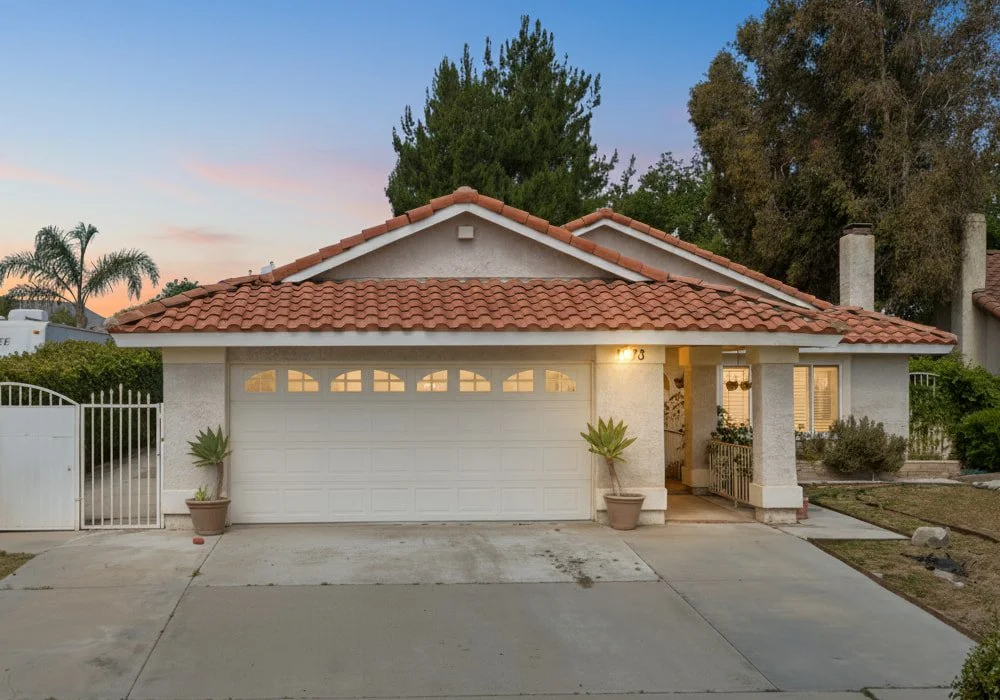 Front exterior view of Golden Acres RCFE II, a single-story assisted living home in Simi Valley, California, with a red-tiled roof, white garage door, and landscaped entryway at sunset