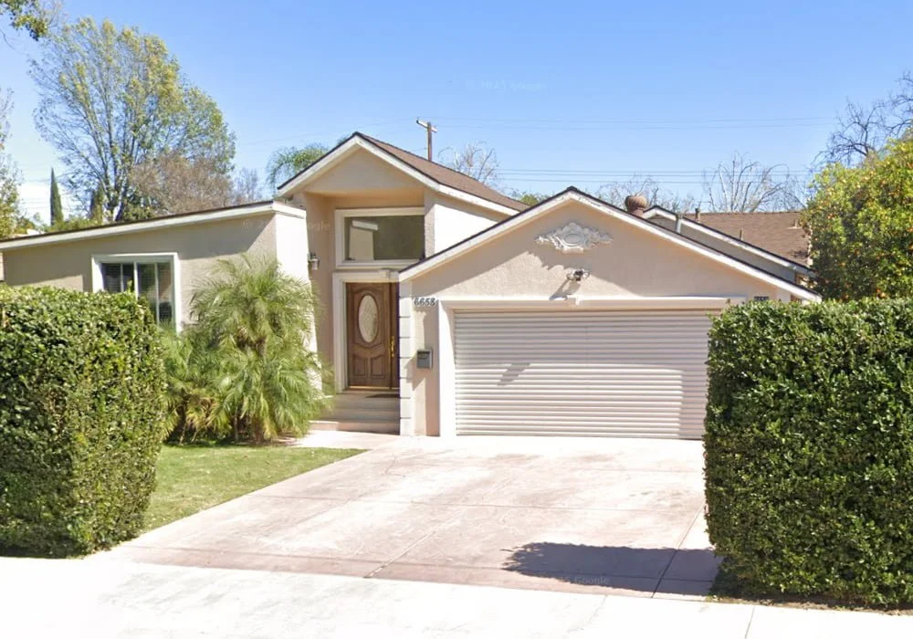 Front exterior of My Serenity Board and Care, a single-story assisted living home with beige walls, trimmed hedges, palm plants, and a closed garage on Capistrano Avenue in West Hills, California.
