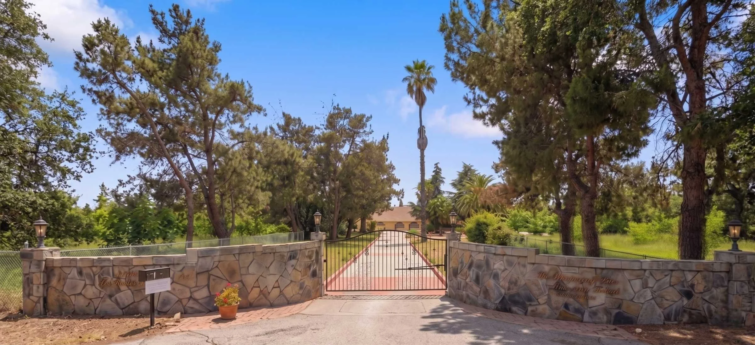 Front view of Whispering Pines Inn, a single-level care home in Hollister, on a sunny day surrounded by green orchards.