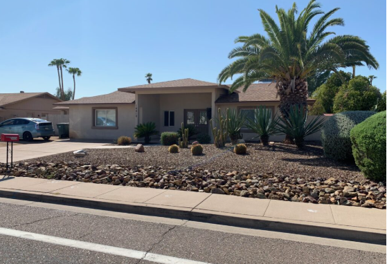 Exterior view of Caring for Loved Ones Assisted Living in Scottsdale, featuring a single-story home with desert landscaping, palm trees, and a welcoming front entrance.