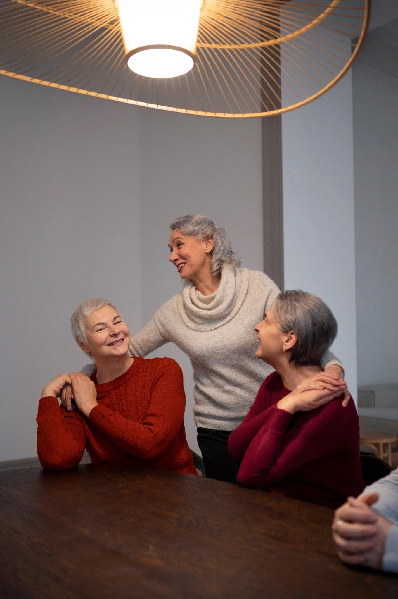 Group of smiling senior women enjoying a warm conversation together at Valley Silvertown, reflecting community, connection, and social well-being in a cozy indoor setting.