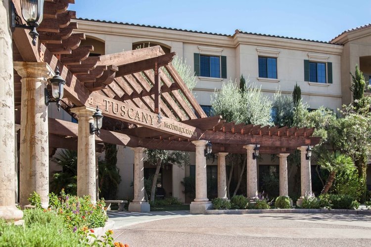 Front entrance of McCormick Ranch Assisted Living Home in Scottsdale, AZ, featuring Mediterranean-style architecture, lush landscaping, and a welcoming covered walkway.