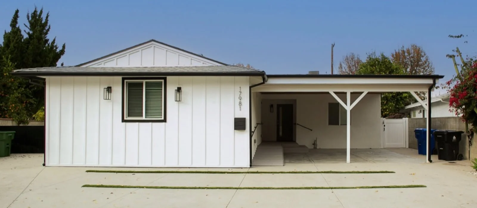 Exterior view of Archwood Assisted Living home with single-story white facade, covered carport, and accessible front entrance