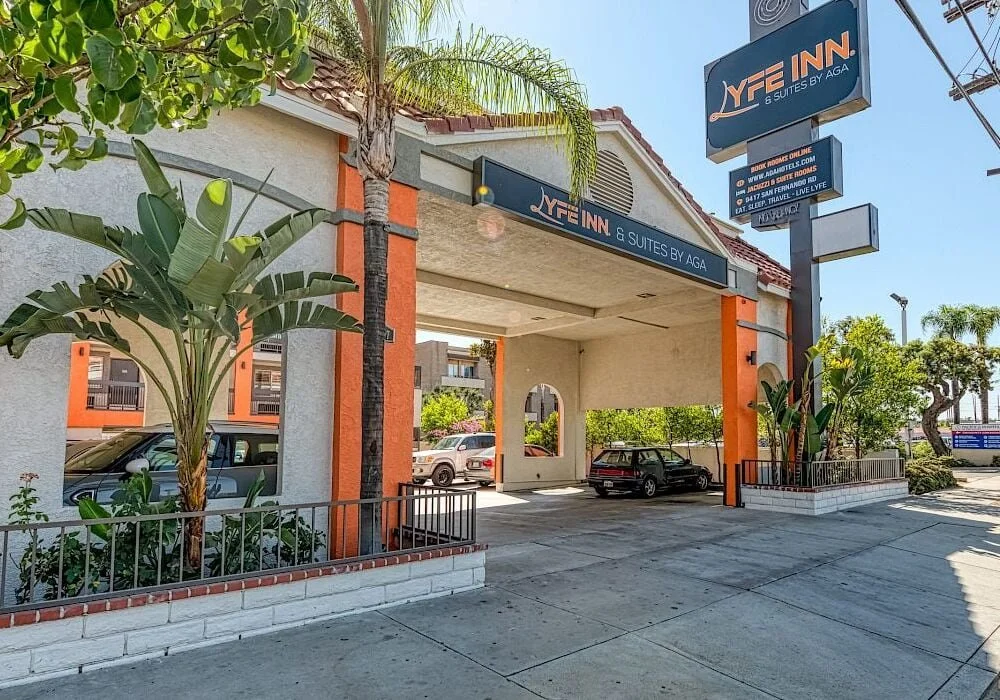 Front view of LYFE INN & Suites by AGA in Sun Valley, Los Angeles, showing the entrance canopy, palm trees, and parking area along San Fernando Road.