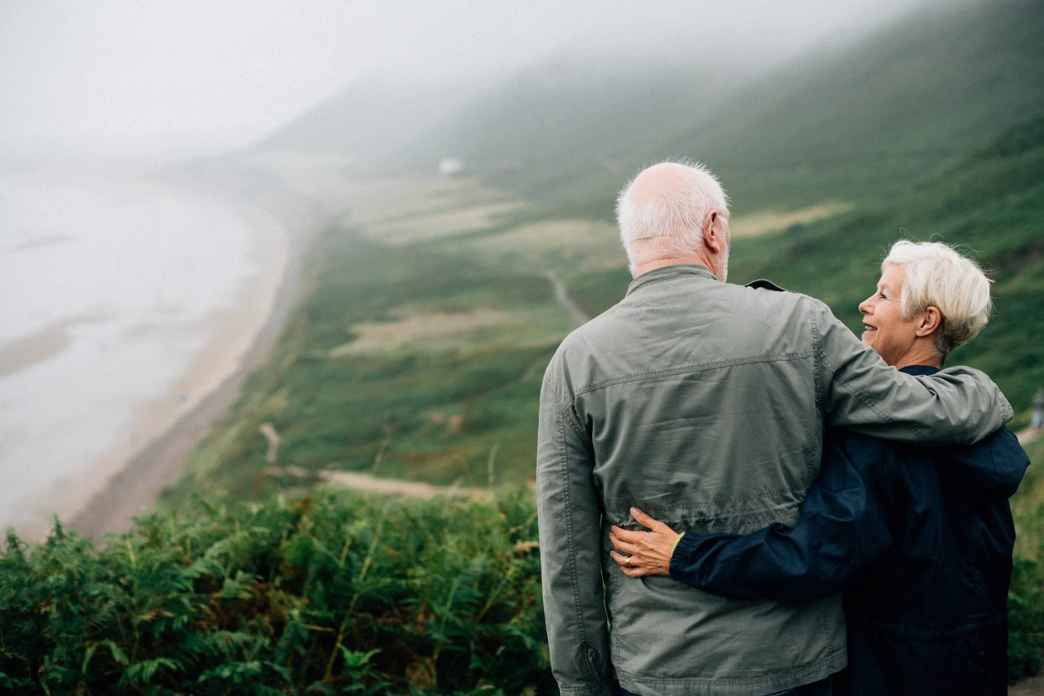 Happy senior couple enjoying a peaceful moment together while admiring a scenic view from a hilltop, symbolizing comfort, care, and companionship in assisted living.