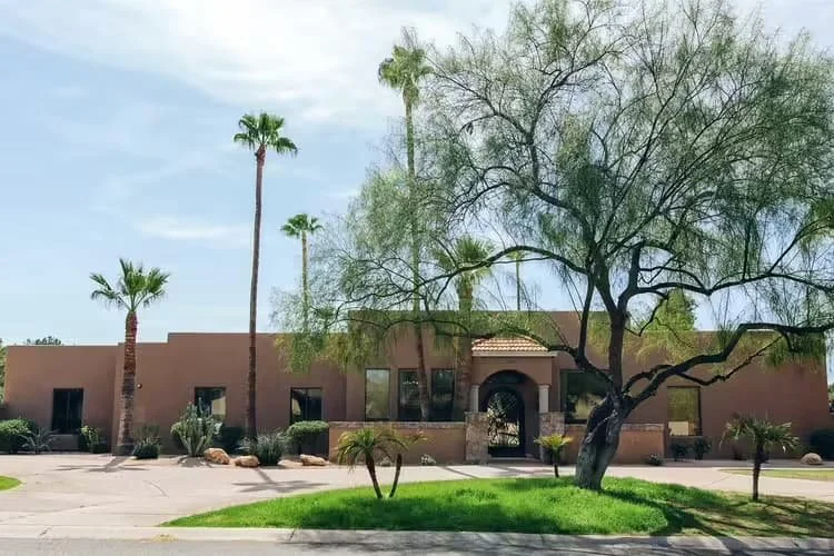 Exterior view of Las Fuentes Assisted Living II in Scottsdale, AZ, featuring desert landscaping, palm trees, and a welcoming residential entrance.