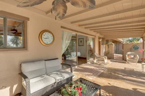 Covered patio seating area at Manor on Paradise Assisted Living, featuring cushioned outdoor furniture, ceiling fans, and natural light for relaxing social gatherings.