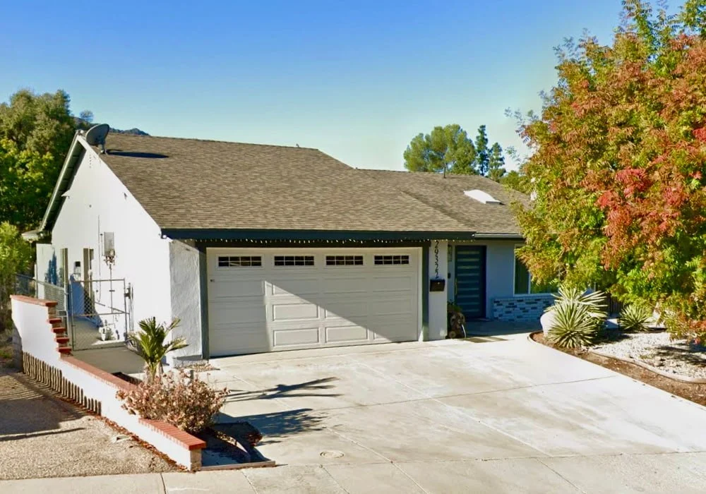 Front exterior of Ladyface View Living assisted living home in Calabasas, California, showing a single-story house with a driveway, garage, and surrounding trees