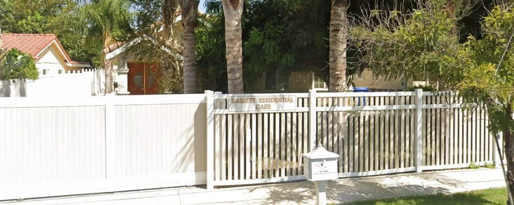 Exterior view of Bassett Residential Care with gated entrance and surrounding trees in a residential neighborhood