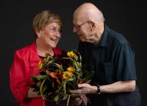 An elderly couple at Fountainview Senior Living sharing a warm moment with a bouquet of flowers, symbolizing love, care, and companionship