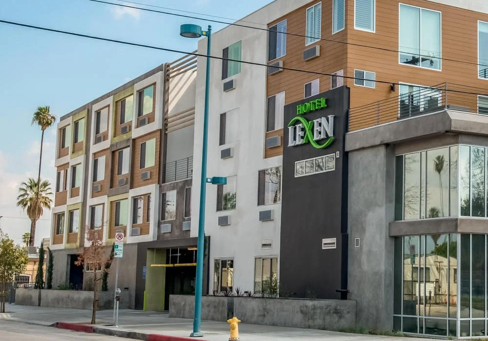 Modern exterior view of Lexen Hotel North Hollywood with glass-front lobby and contemporary facade on Tujunga Avenue, Los Angeles.
