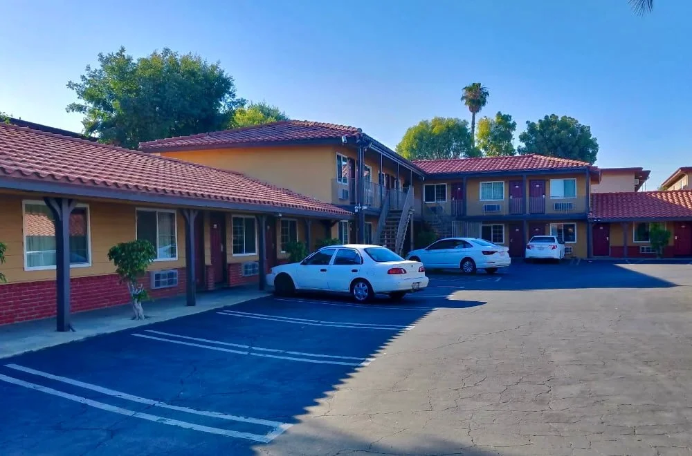 Exterior view of Panorama Motel in Panorama City, Los Angeles — two-story building with red tile roof, parking area, and guest rooms with outdoor entrances.