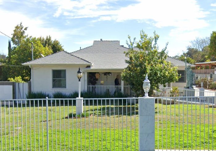 Front view of Advanced Home Care Senior Living house with white fence and green lawn in Woodland Hills, California