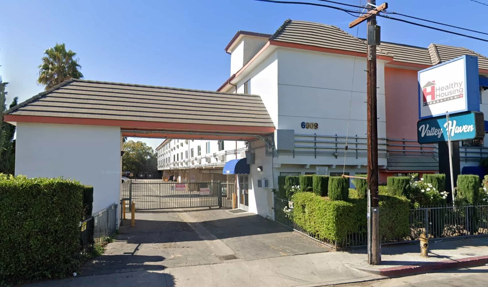 Gated exterior entrance of Valley Haven housing on Sepulveda Boulevard in Van Nuys with Healthy Housing Foundation sign visible