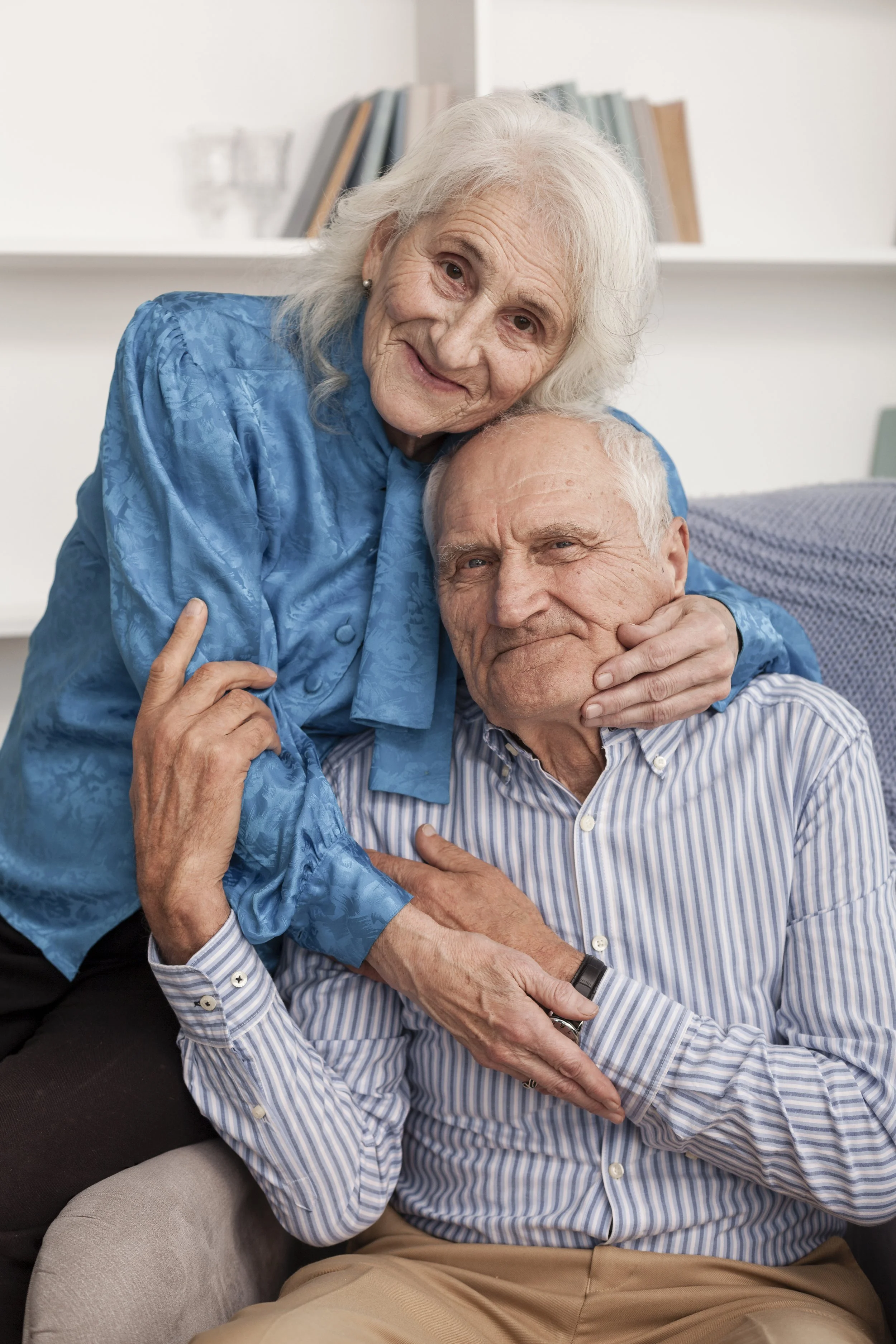Smiling senior couple embracing each other warmly at Savant Burbank East, seated together in a cozy, light-filled living space that reflects comfort and connection.