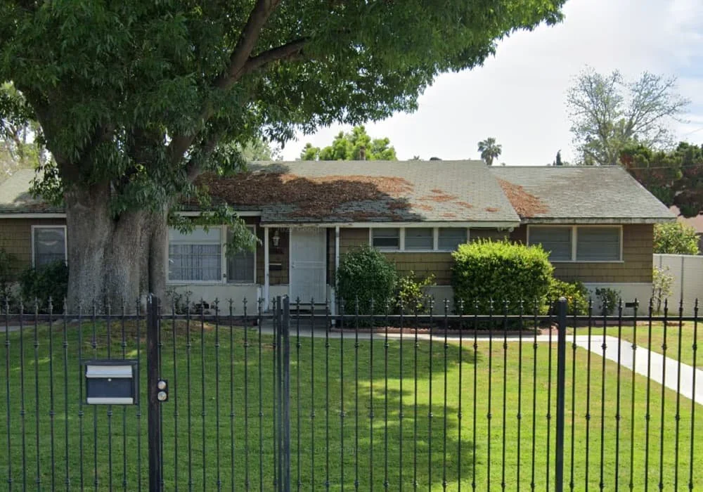 Single-story residential care home with large front tree, fenced green lawn, and paved walkway in Lake Balboa, California.