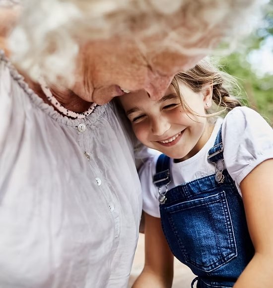 Close-up of a smiling grandmother and granddaughter sharing a joyful moment at Savant Tarzana, reflecting warmth, connection, and multi-generational bonding.