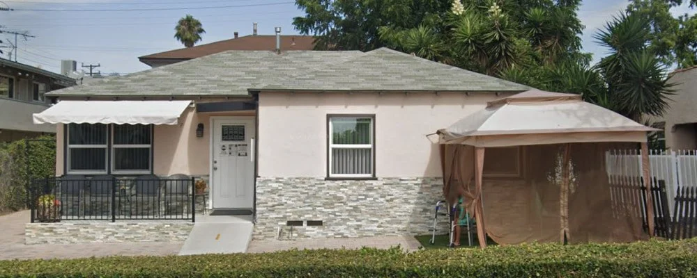Exterior view of Arego Home Inc, a single-story residential care home with front entrance and shaded patio area