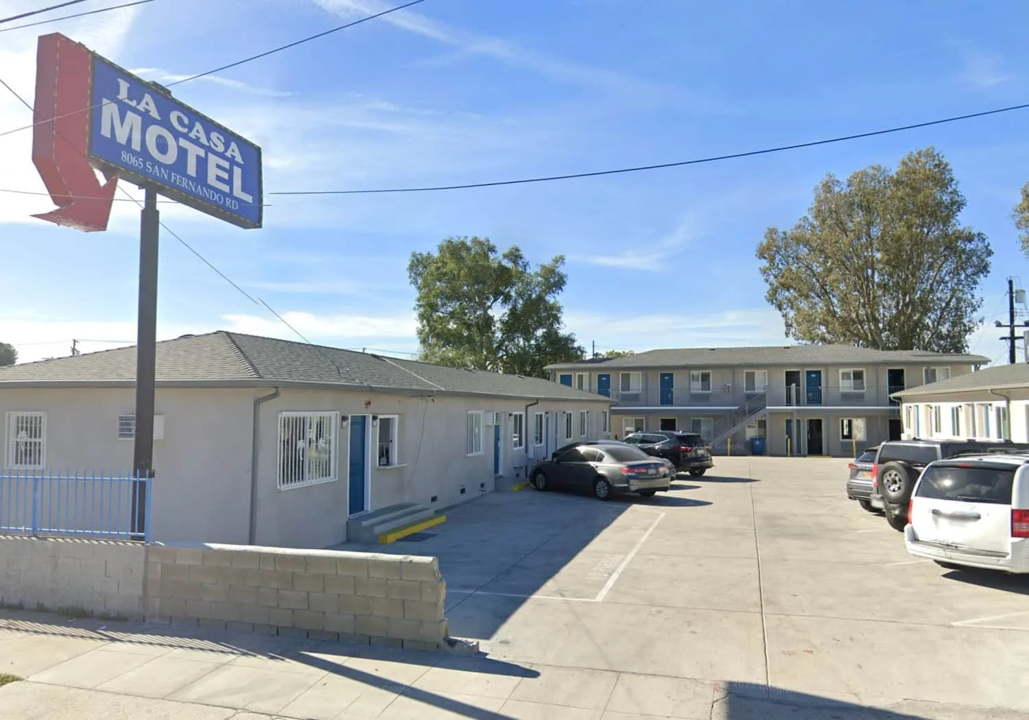 La Casa Motel in Sun Valley, California, showing the front sign, single- and two-story buildings, and parking lot with parked cars under a clear blue sky.