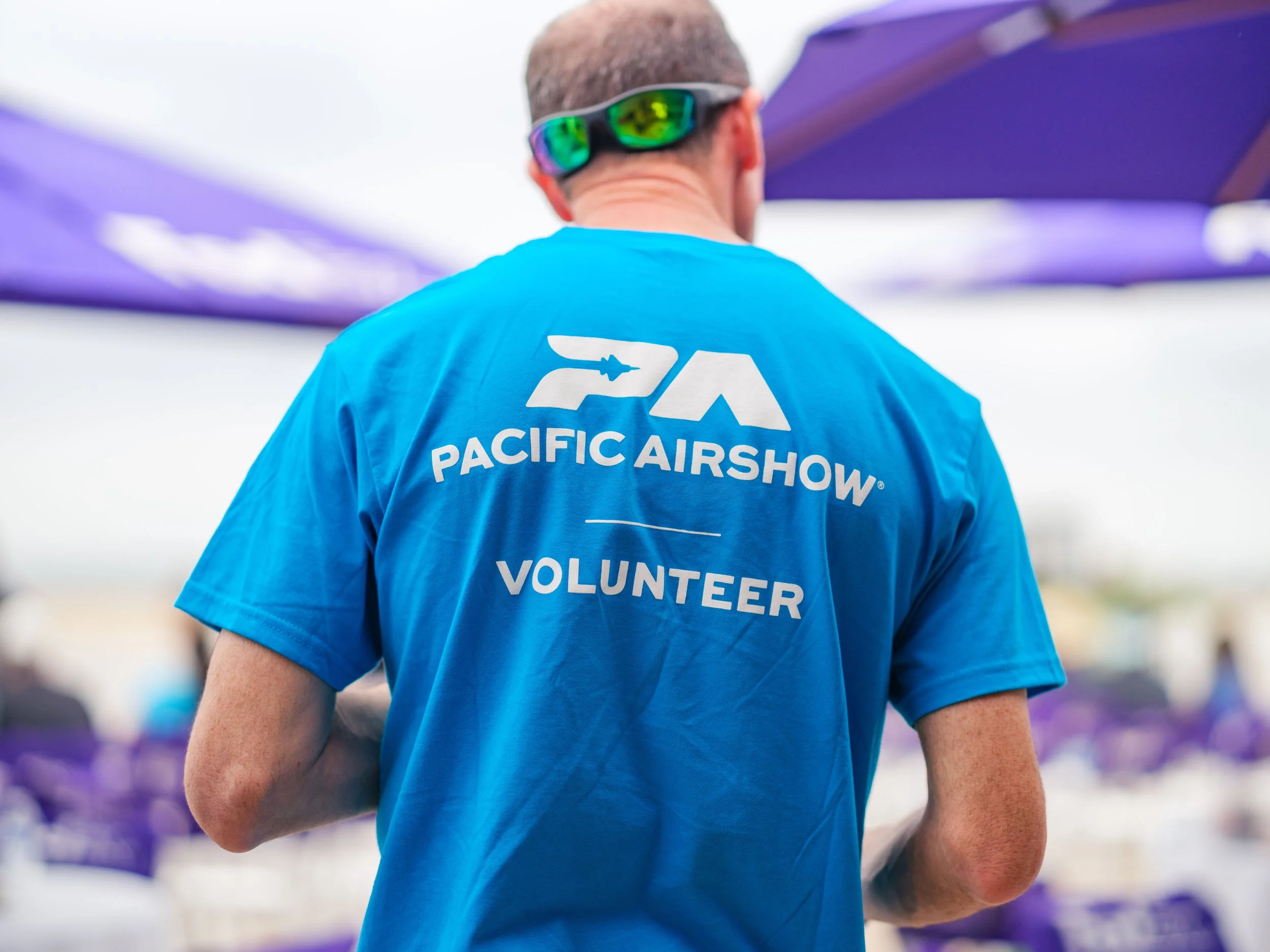 Pacific Airshow Volunteer in a Blue Volunteer T-Shirt.