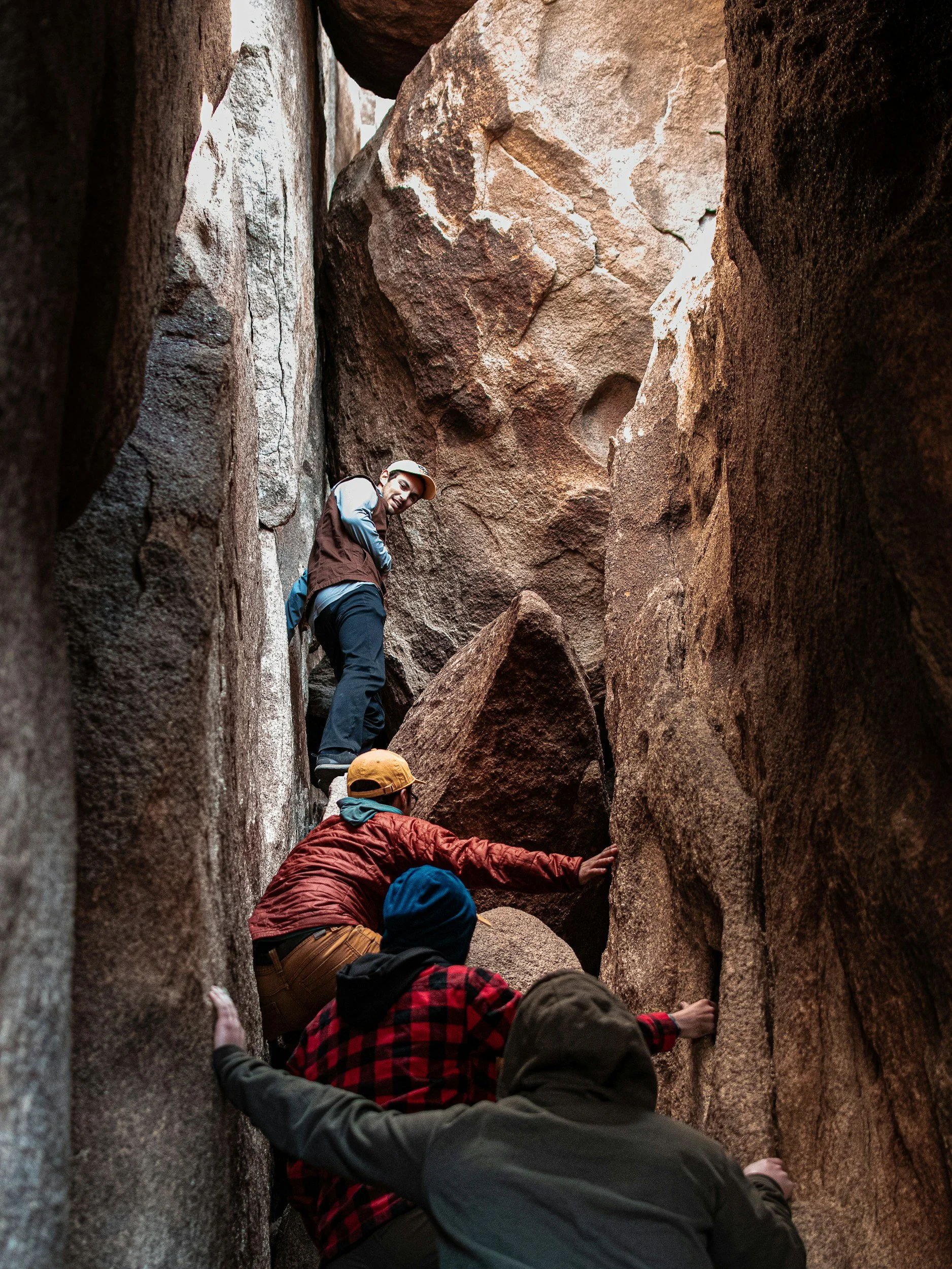 Four people climbing in a narrow, rocky canyon.