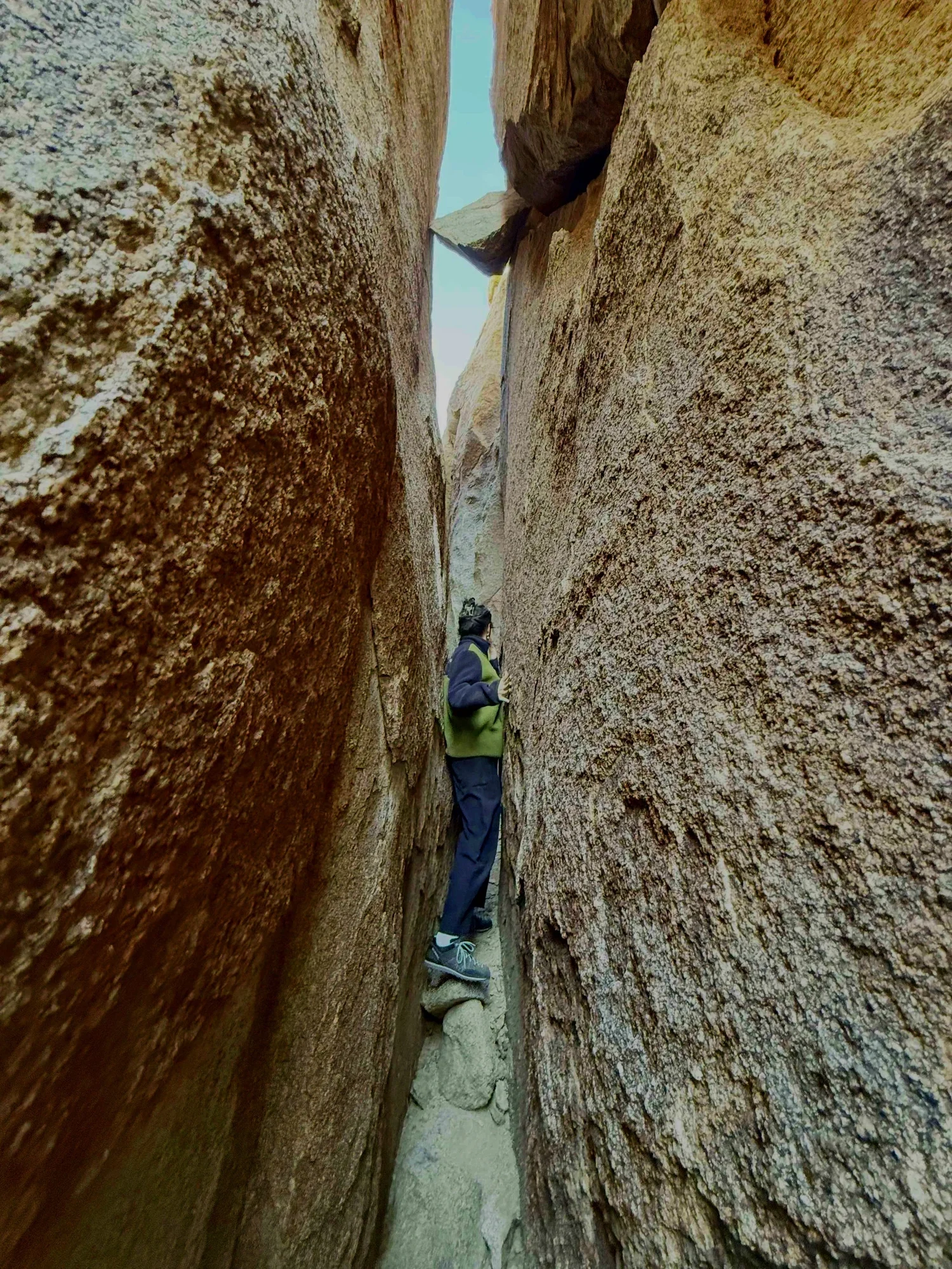 A person standing between two tall narrow granite rock formations on The Great Misdirect corridor