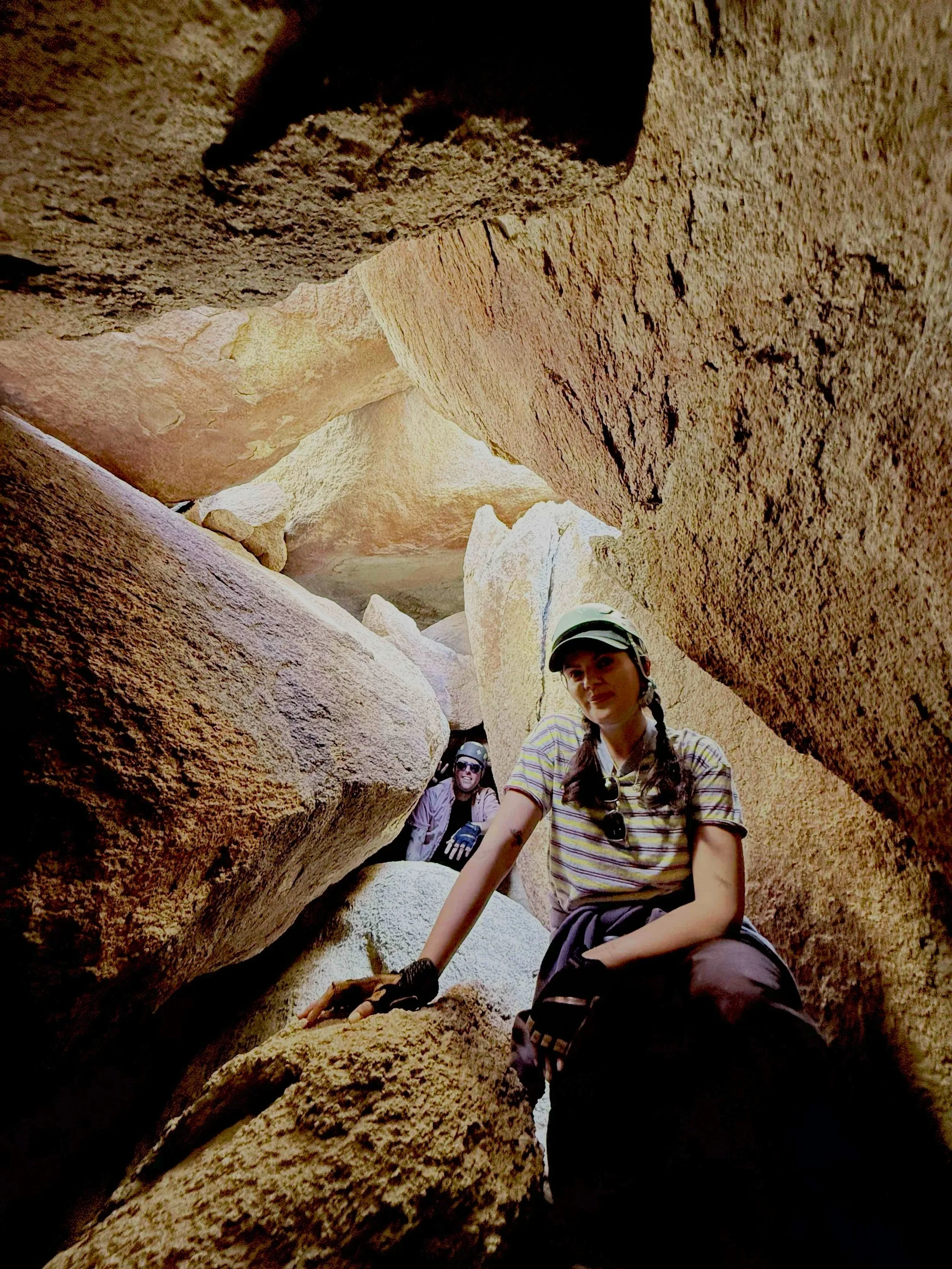 People rappelling down a rocky canyon, wearing helmets and harnesses.