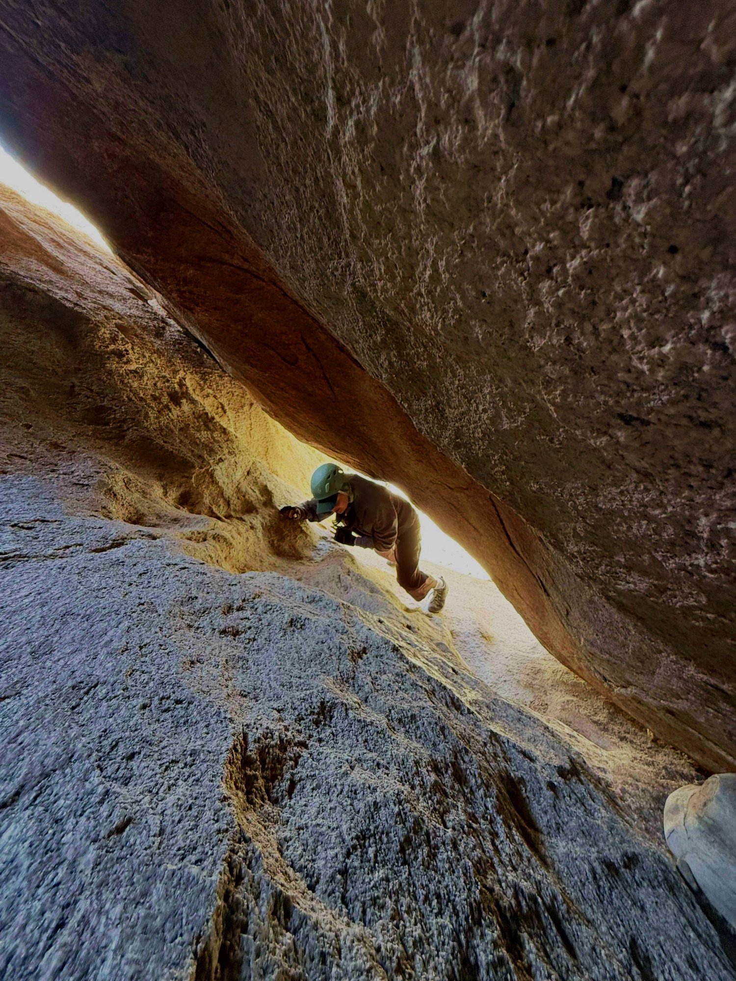 Person in a helmet navigating a narrow rocky crevice — the S3 rating in action on The Mad Hatter entrance cave