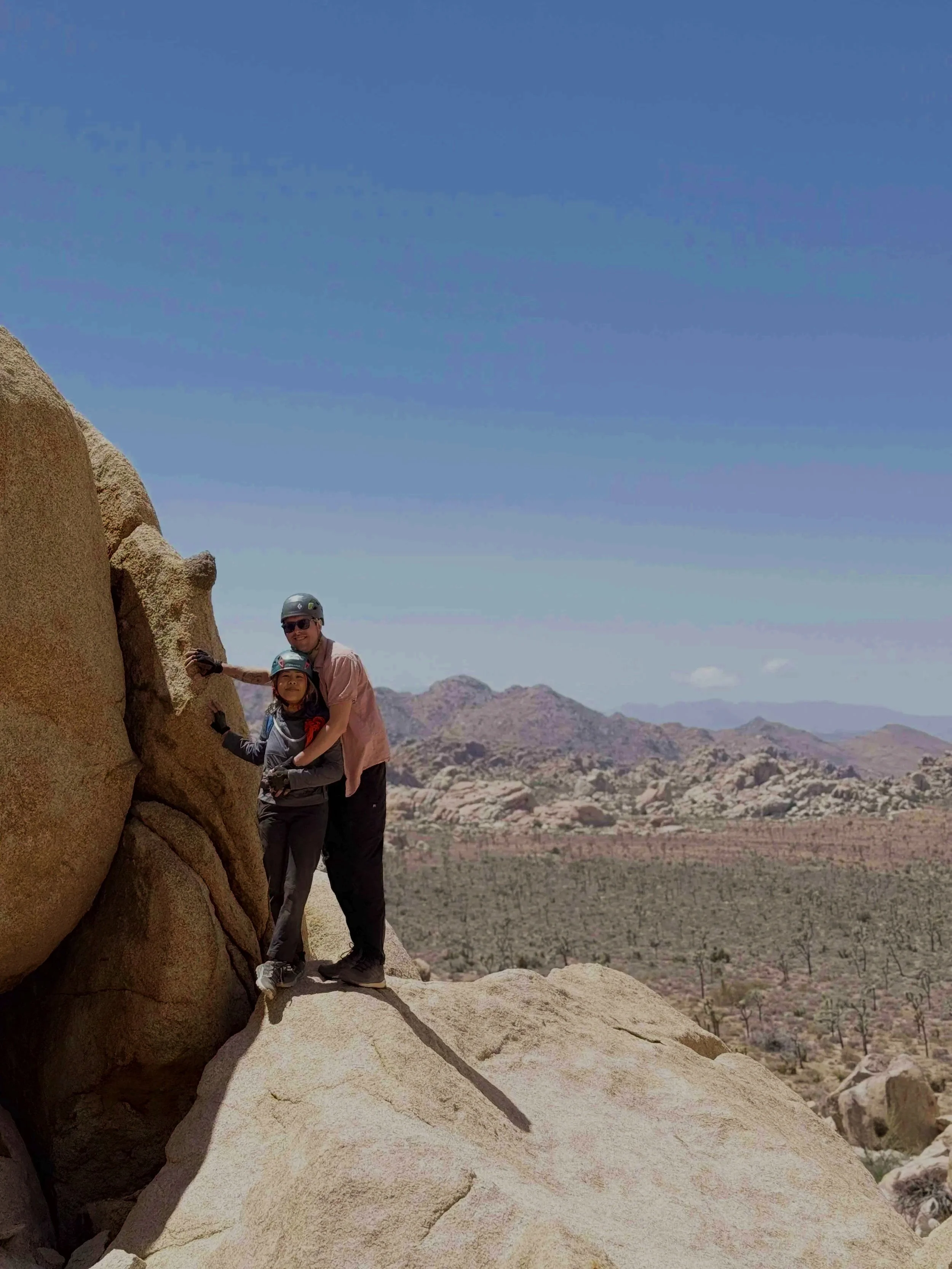 Two adults and a child standing on rocks in a Joshua Tree desert landscape after completing The Mad Hatter adventure