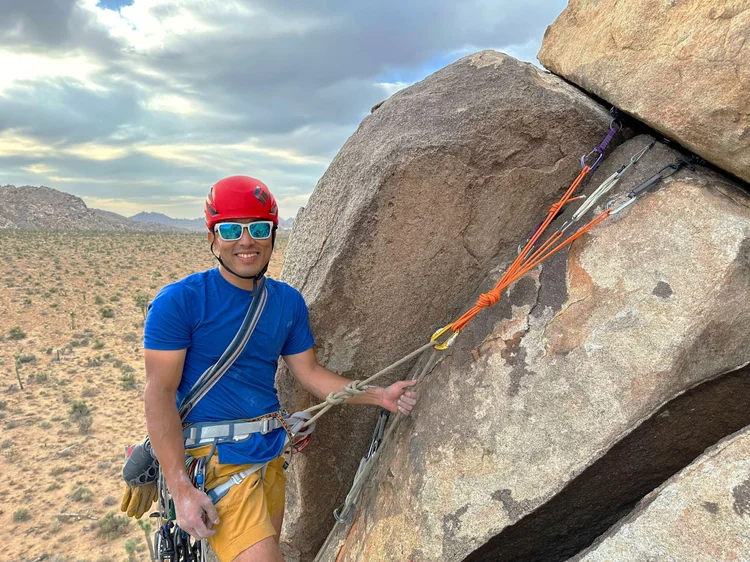 Guide holding climbing gear next to granite rock formations in Joshua Tree