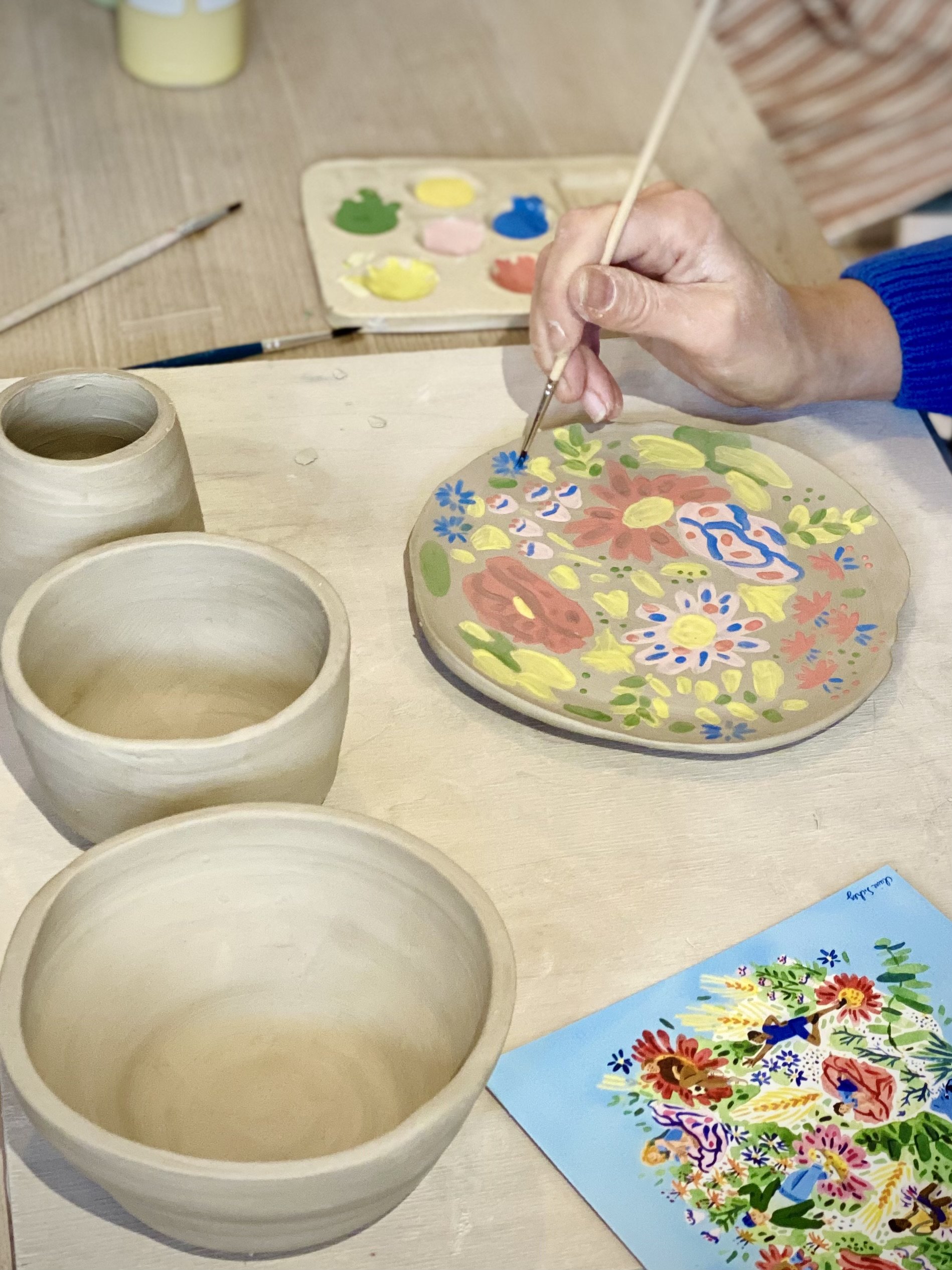 Étapes de fabrication de poteries en argile avec plusieurs bols, vases et outils de sculpture en céramique sur une table. Dessins et mesures pour la création de formes en argile visible à l'arrière-plan.